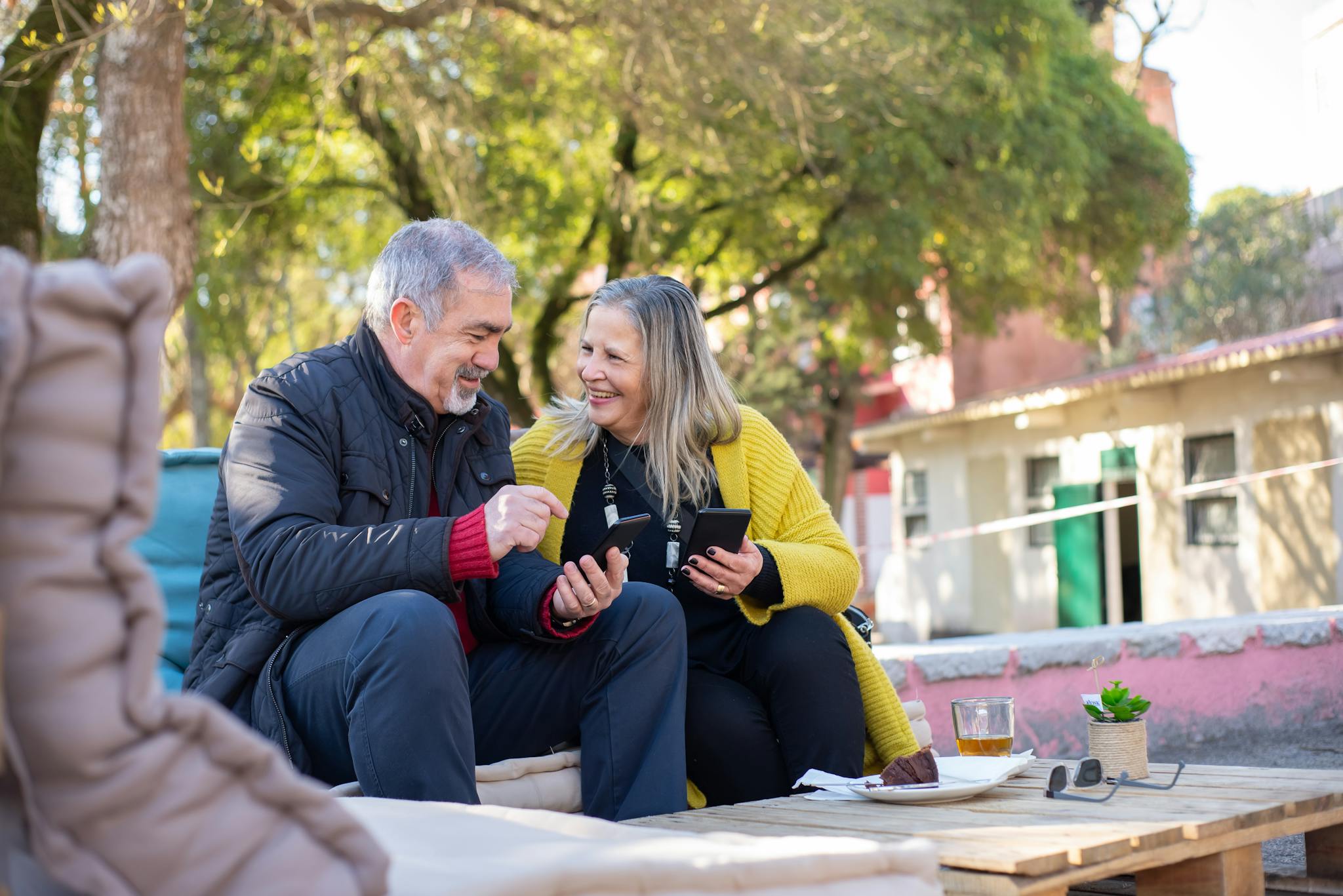 Smiling senior couple enjoying a cup of tea outdoors, cherishing a moment of happiness in a park in Portugal.